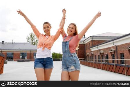 leisure and friendship concept - happy smiling teenage girls or best friends in sunglasses hugging and waving hands on city street in summer. teenage girls or friends on city street in summer