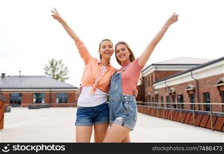 leisure and friendship concept - happy smiling teenage girls or best friends in sunglasses hugging and showing peace gesture on city roof top in summer. teenage girls or friends on city roof top