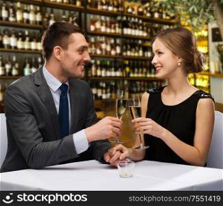 leisure and luxury concept - smiling couple clinking glasses of champagne over restaurant or wine bar background. couple with glasses of champagne at restaurant