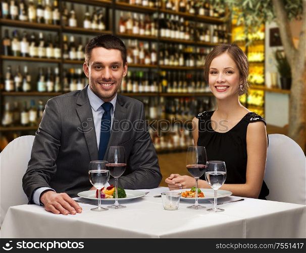 leisure and luxury concept - smiling couple with food and wine over restaurant or wine bar background. smiling couple with food and wine at restaurant