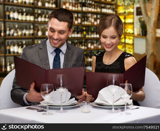 leisure and luxury concept - smiling couple with menus over restaurant or wine bar background. smiling couple with menus at restaurant