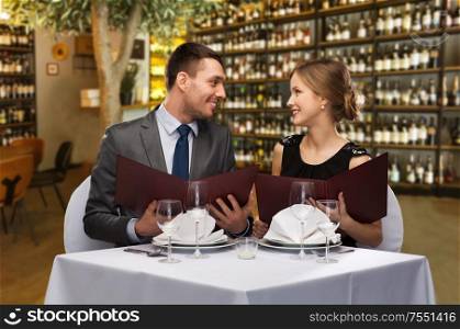 leisure and luxury concept - smiling couple with menus over restaurant or wine bar background. happy couple with menus at restaurant or wine bar