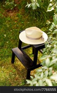 leisure and objects concept - close up of straw hat on stool at summer garden. close up of straw hat on stool at summer garden