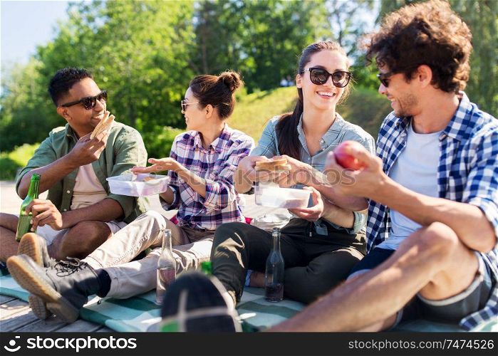 leisure and people concept - group of happy friends having picnic and eating sandwiches at summer park. happy friends having picnic at summer park