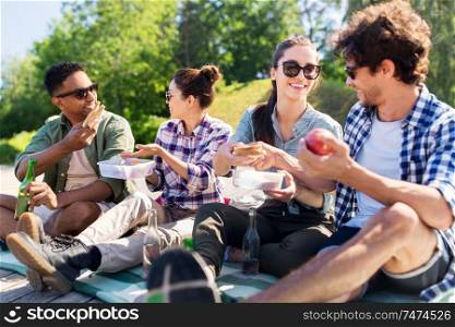 leisure and people concept - group of happy friends having picnic and eating sandwiches at summer park. happy friends having picnic at summer park