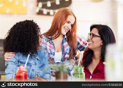 leisure and people concept - group of happy international female friends with drinks at bar or restaurant. happy female friends with drinks at bar
