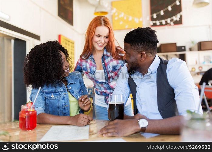 leisure and people concept - group of happy international friends with drinks at bar or restaurant. happy friends with drinks at bar or restaurant