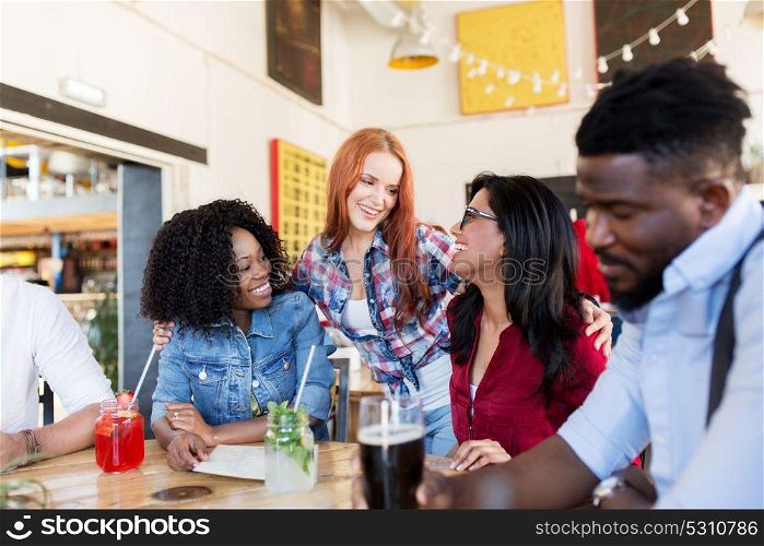 leisure and people concept - group of happy international friends with drinks at bar or restaurant. happy friends with drinks at bar or restaurant