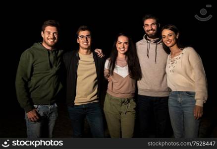 leisure and people concept - group of happy smiling friends outdoors at night. group of happy smiling friends outdoors at night