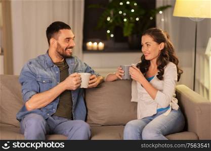 leisure and people concept - happy couple drinking tea or coffee at home. happy couple drinking tea or coffee at home