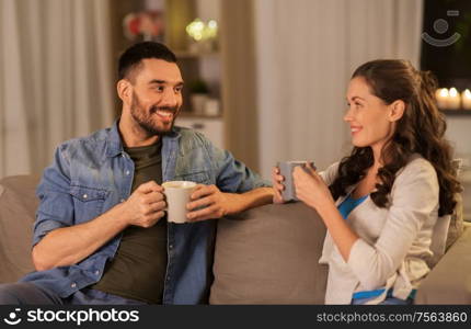 leisure and people concept - happy couple drinking tea or coffee at home. happy couple drinking tea or coffee at home