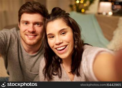 leisure and people concept - happy couple taking selfie at home. happy couple taking selfie at home