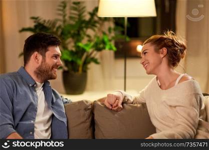 leisure and people concept - happy couple talking at home in evening. happy couple talking at home in evening