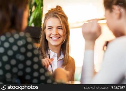 leisure and people concept - happy female friends sitting and talking at cafe or restaurant. happy friends sitting and talking at cafe