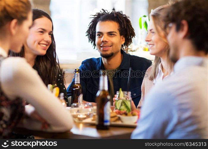 leisure and people concept - happy friends eating and drinking non-alcoholic drinks at bar or restaurant. happy friends eating at bar or restaurant