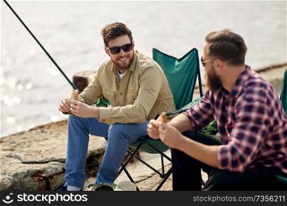 leisure and people concept - happy friends fishing and eating sandwiches on pier at sea. happy friends fishing and eating sandwiches