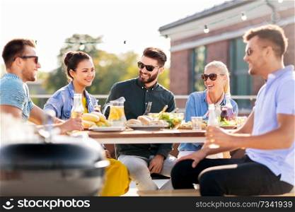 leisure and people concept - happy friends having barbecue party on rooftop in summer. happy friends having bbq party on rooftop