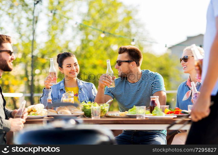 leisure and people concept - happy friends having dinner or bbq party on rooftop in summer. friends having dinner or bbq party on rooftop