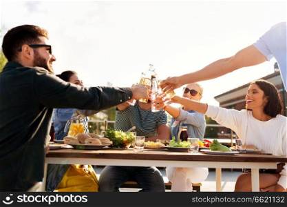 leisure and people concept - happy friends toasting drinks at rooftop party in summer. happy friends toasting drinks at rooftop party
