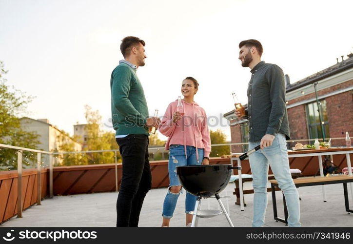 leisure and people concept - happy friends with bbq grill and non alcoholic drinks having barbecue party on rooftop. happy friends having bbq party on rooftop