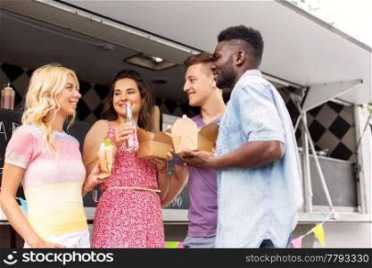 leisure and people concept - happy friends with drinks eating and talking at food truck. happy friends with drinks eating at food truck