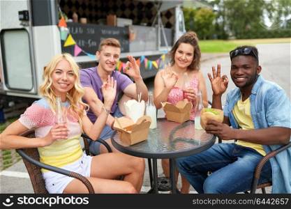 leisure and people concept - happy friends with drinks eating at food truck showing ok hand sign. happy friends with drinks eating at food truck