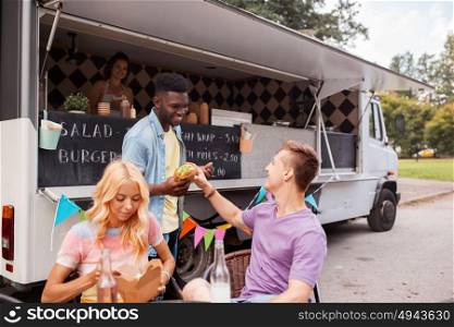 leisure and people concept - happy friends with drinks eating at food truck. happy friends with drinks eating at food truck