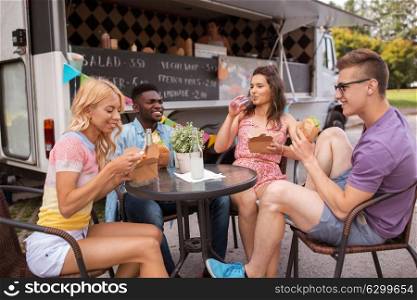 leisure and people concept - happy friends with drinks eating at food truck. happy friends with drinks eating at food truck