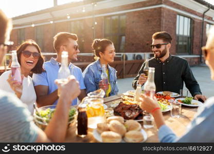 leisure and people concept - happy friends with drinks having barbecue party on rooftop. happy friends with drinks or bbq party on rooftop