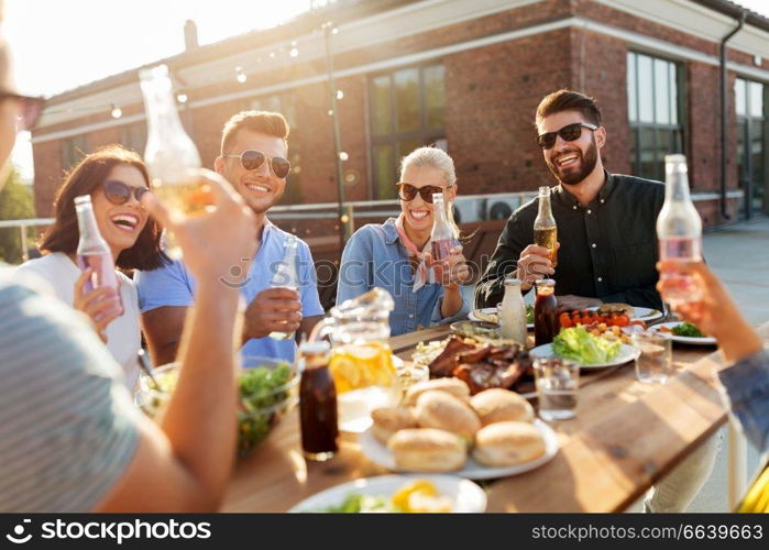 leisure and people concept - happy friends with drinks having barbecue party on rooftop. happy friends with drinks or bbq party on rooftop