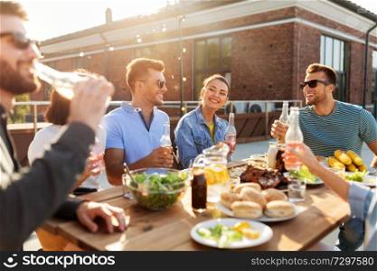 leisure and people concept - happy friends with drinks having barbecue party on rooftop. happy friends with drinks or bbq party on rooftop