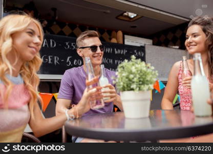 leisure and people concept - happy friends with drinks sitting at table at food truck. friends with drinks sitting at table at food truck