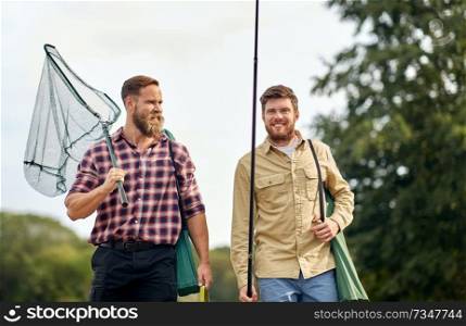 leisure and people concept - happy friends with fishing rods and scoop net outdoors. friends with fishing rods and net outdoors