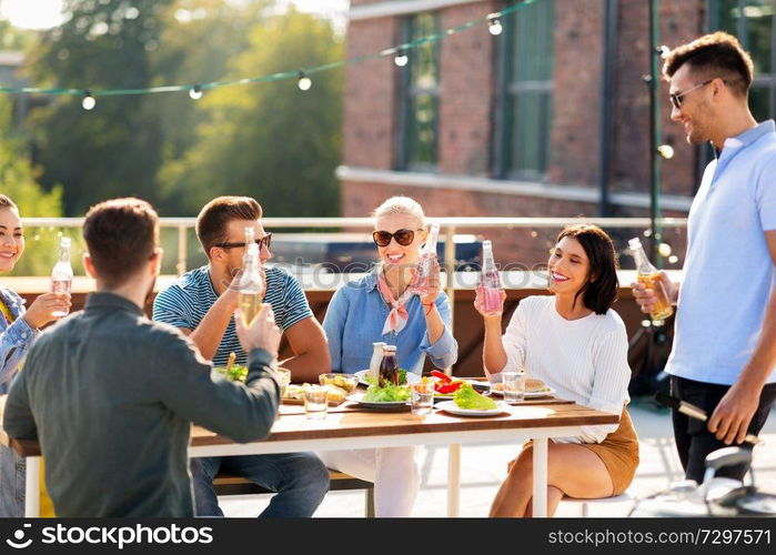 leisure and people concept - happy friends with non alcoholic drinks having barbecue party on rooftop. happy friends with drinks or bbq party on rooftop