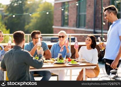 leisure and people concept - happy friends with non alcoholic drinks having barbecue party on rooftop. happy friends with drinks or bbq party on rooftop