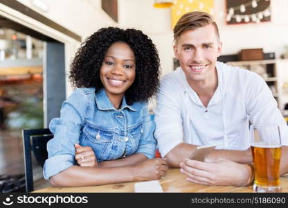 leisure and people concept - happy man and woman with smartphone and drinks at bar or restaurant. happy man and woman with smartphone at bar