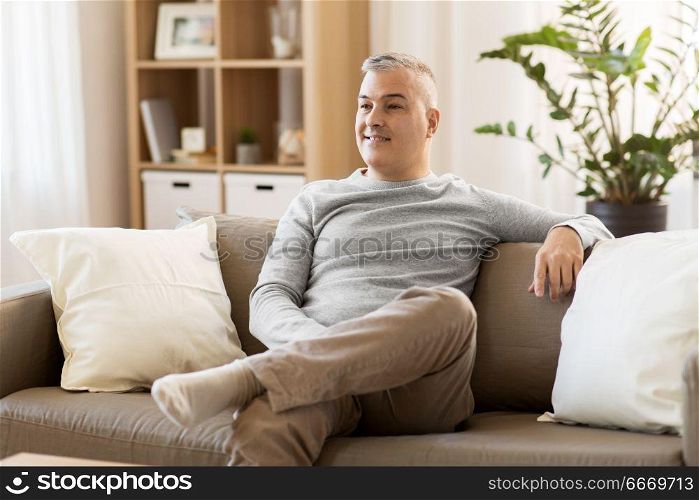 leisure and people concept - happy middle-aged man sitting on sofa at home. happy middle-aged man sitting on sofa at home. happy middle-aged man sitting on sofa at home