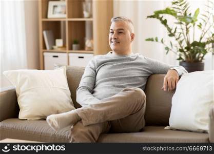 leisure and people concept - happy middle-aged man sitting on sofa at home. happy middle-aged man sitting on sofa at home. happy middle-aged man sitting on sofa at home