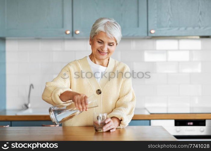 leisure and people concept - happy smiling woman pouring water from jug to drinking glass on kitchen at home. happy woman with jug of water on kitchen at home