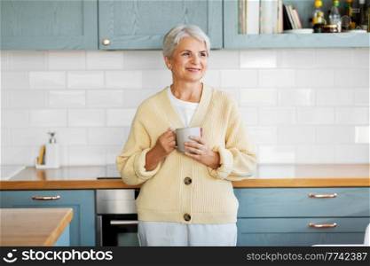 leisure and people concept - happy smiling woman with cup of coffee on kitchen at home. happy woman with cup of coffee on kitchen at home
