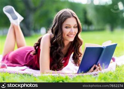 leisure and people concept - happy smiling young woman reading book at summer park. happy smiling woman reading book at summer park