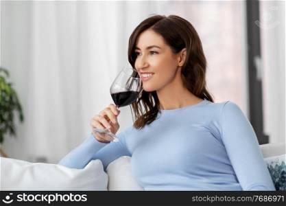 leisure and people concept - happy woman drinking red wine at home. happy woman drinking red wine at home