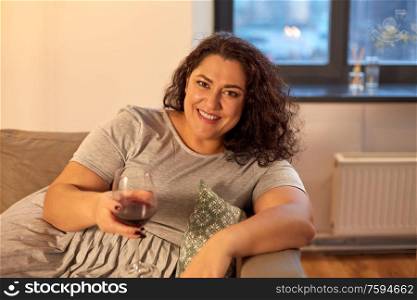 leisure and people concept - happy woman drinking red wine at home in evening. happy woman drinking red wine at home in evening