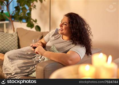 leisure and people concept - happy woman drinking red wine at home in evening. happy woman drinking red wine at home in evening
