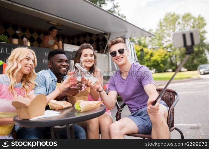 leisure and people concept - happy young friends with food and drinks and taking selfie at food truck. happy young friends taking selfie at food truck