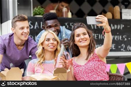 leisure and people concept - happy young friends with food and non alcoholic drinks and taking selfie at food truck. happy young friends taking selfie at food truck