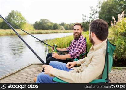 leisure and people concept - male friends fishing and drinking beer on lake. male friends fishing and drinking beer on lake