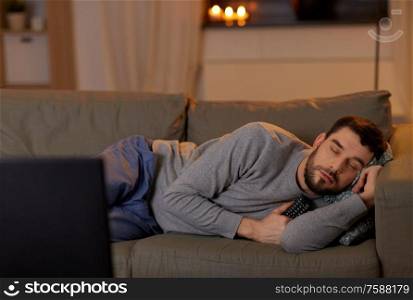 leisure and people concept - man sleeping on sofa with tv remote control at home at night. man sleeping on sofa with tv remote at home