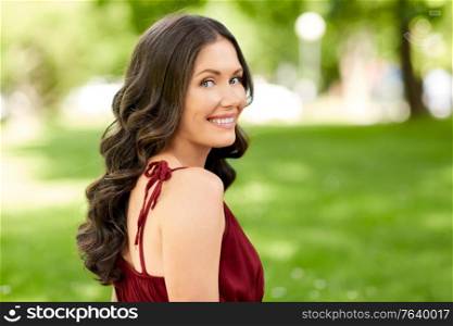 leisure and people concept - portrait of happy smiling woman with long wavy hair at summer park. portrait of happy smiling woman at summer park