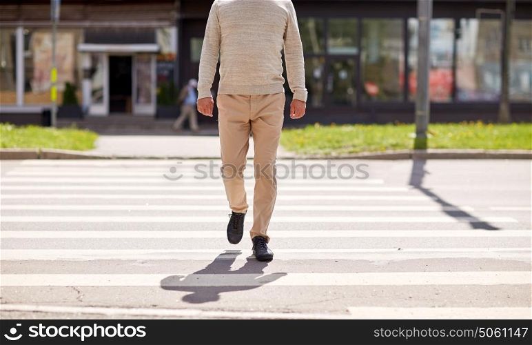 leisure and people concept - senior man walking along summer city crosswalk. senior man walking along city crosswalk